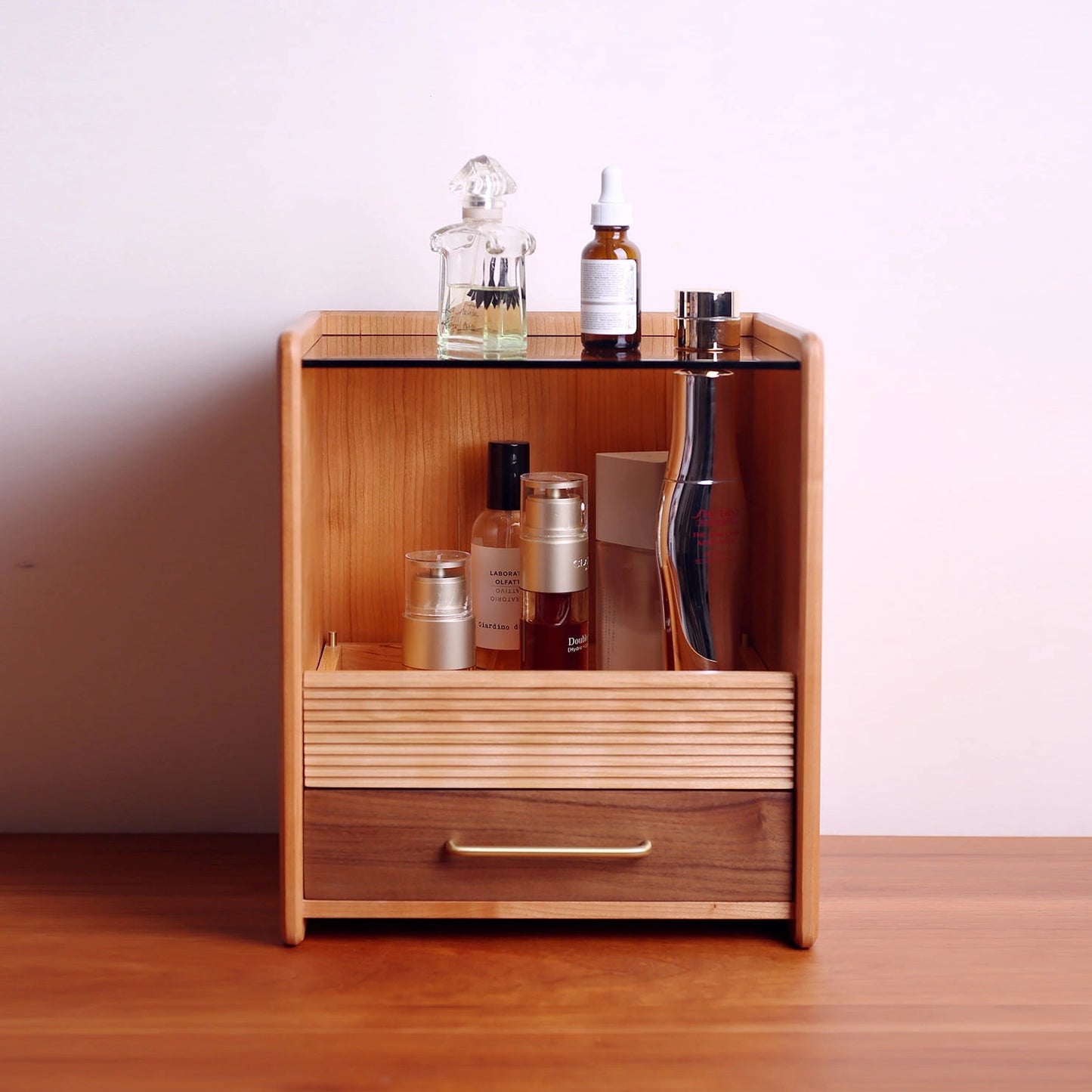 Wood vanity organizer storing perfume, skincare, and cosmetic bottles.