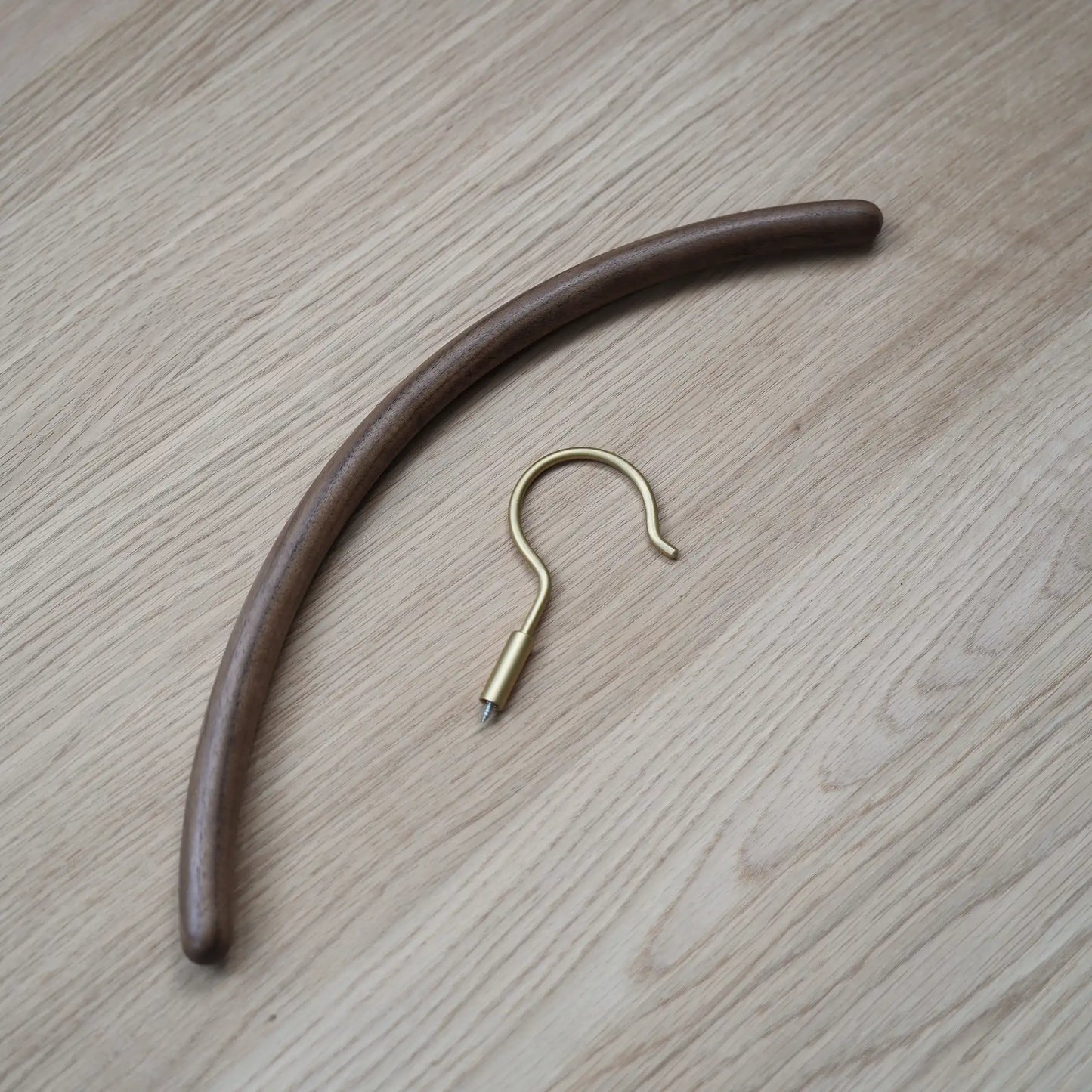 A disassembled view of the walnut hanger body and the brass screw-in hook.