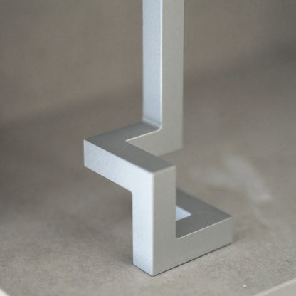 Close-up of a silver aluminum opener's geometric base on a shelf.