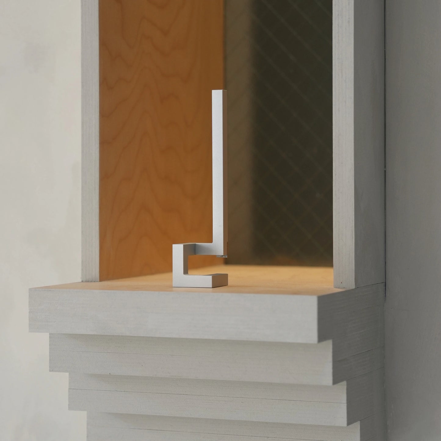 Silver geometric opener standing as decor inside a wooden display box.