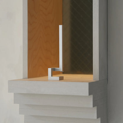 Silver geometric opener standing as decor inside a wooden display box.