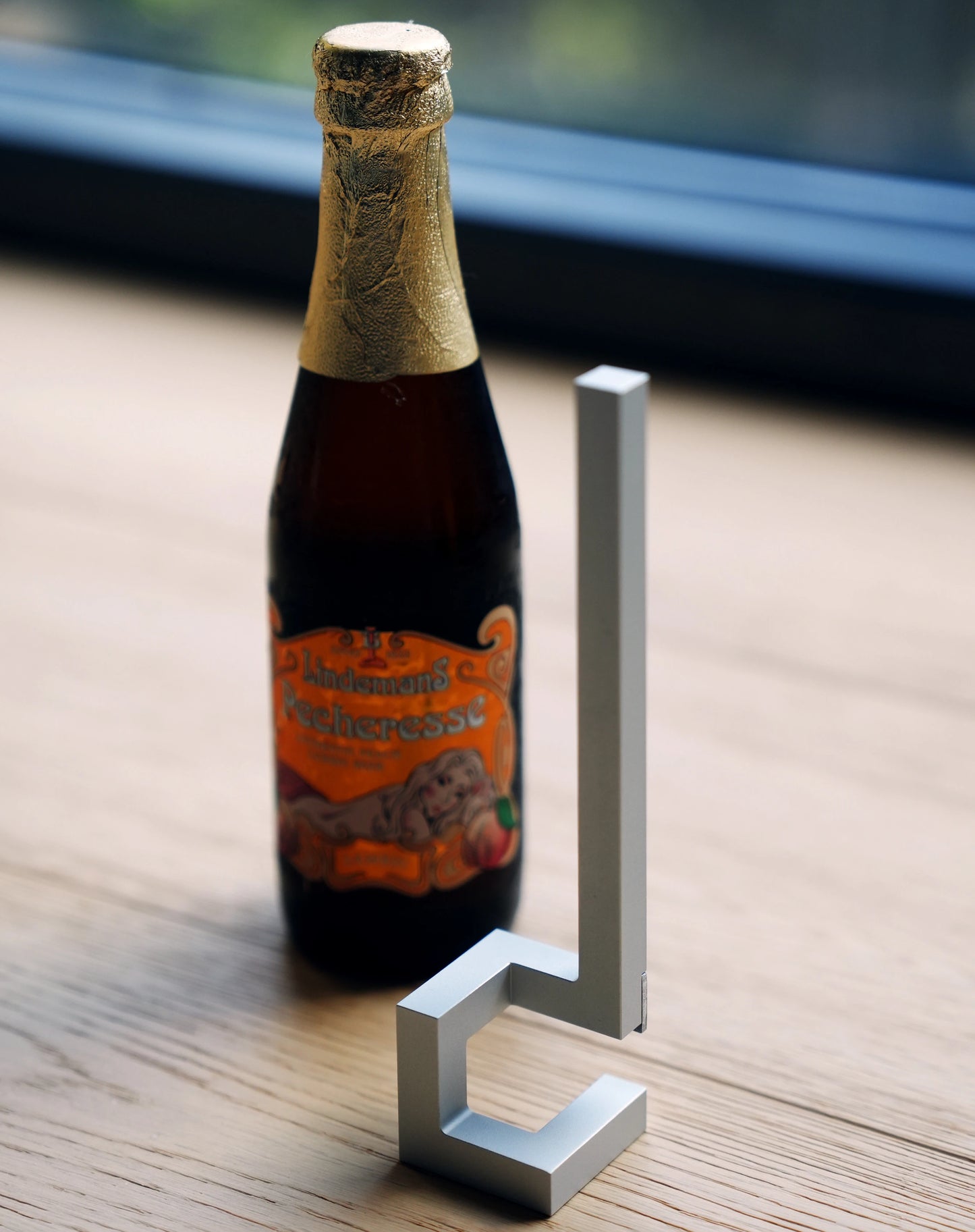 Modern silver bar tool standing beside a  beer bottle.