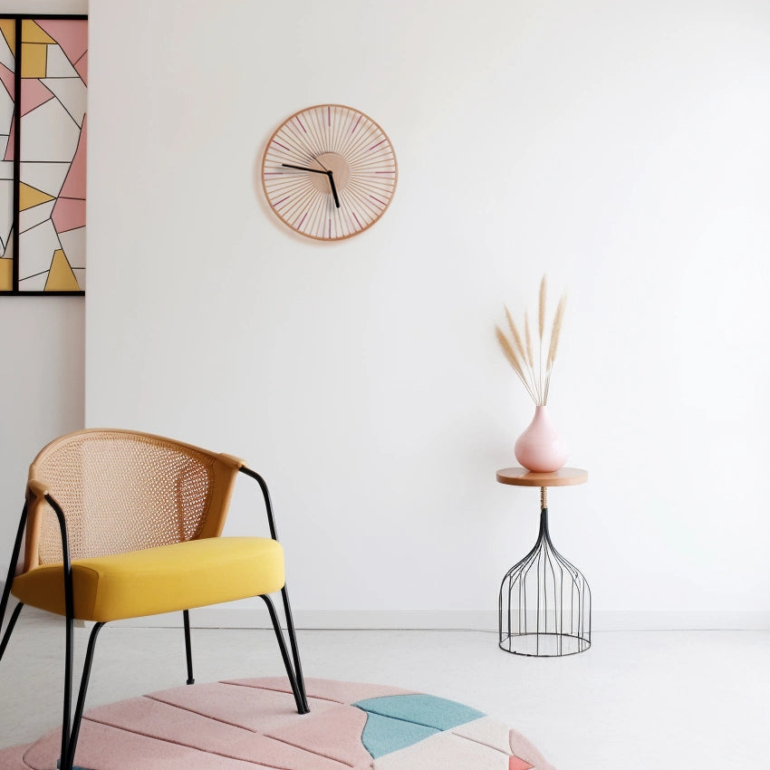 A bamboo wall clock styled in a modern room with a yellow chair.