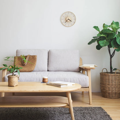 A natural bamboo wall clock hanging in a Japandi-style living room.