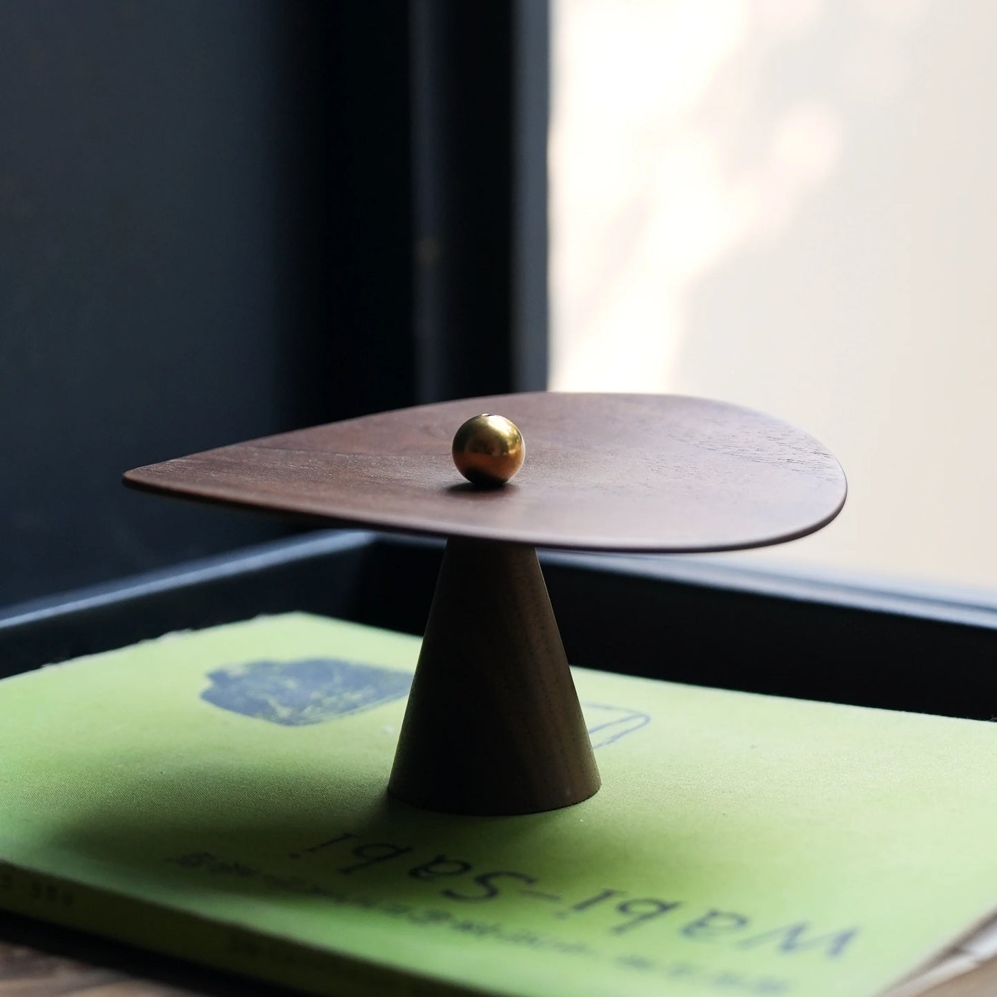 Walnut incense holder on a book, showing cone base and curved plate.