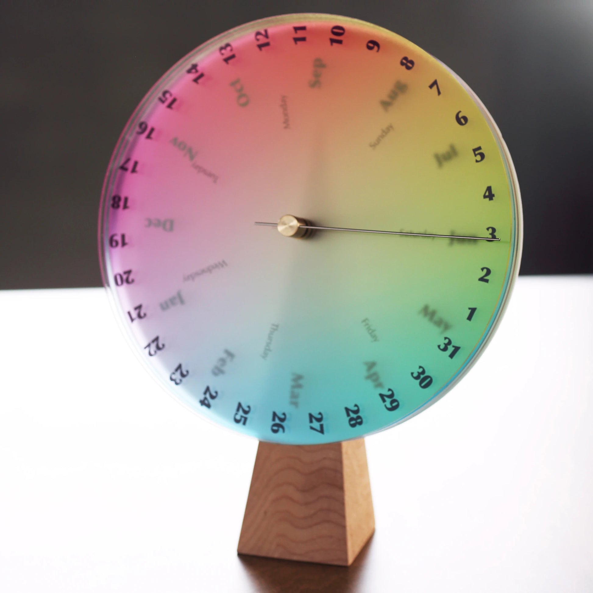 Full view of the rainbow color wheel perpetual calendar on a wood desk.