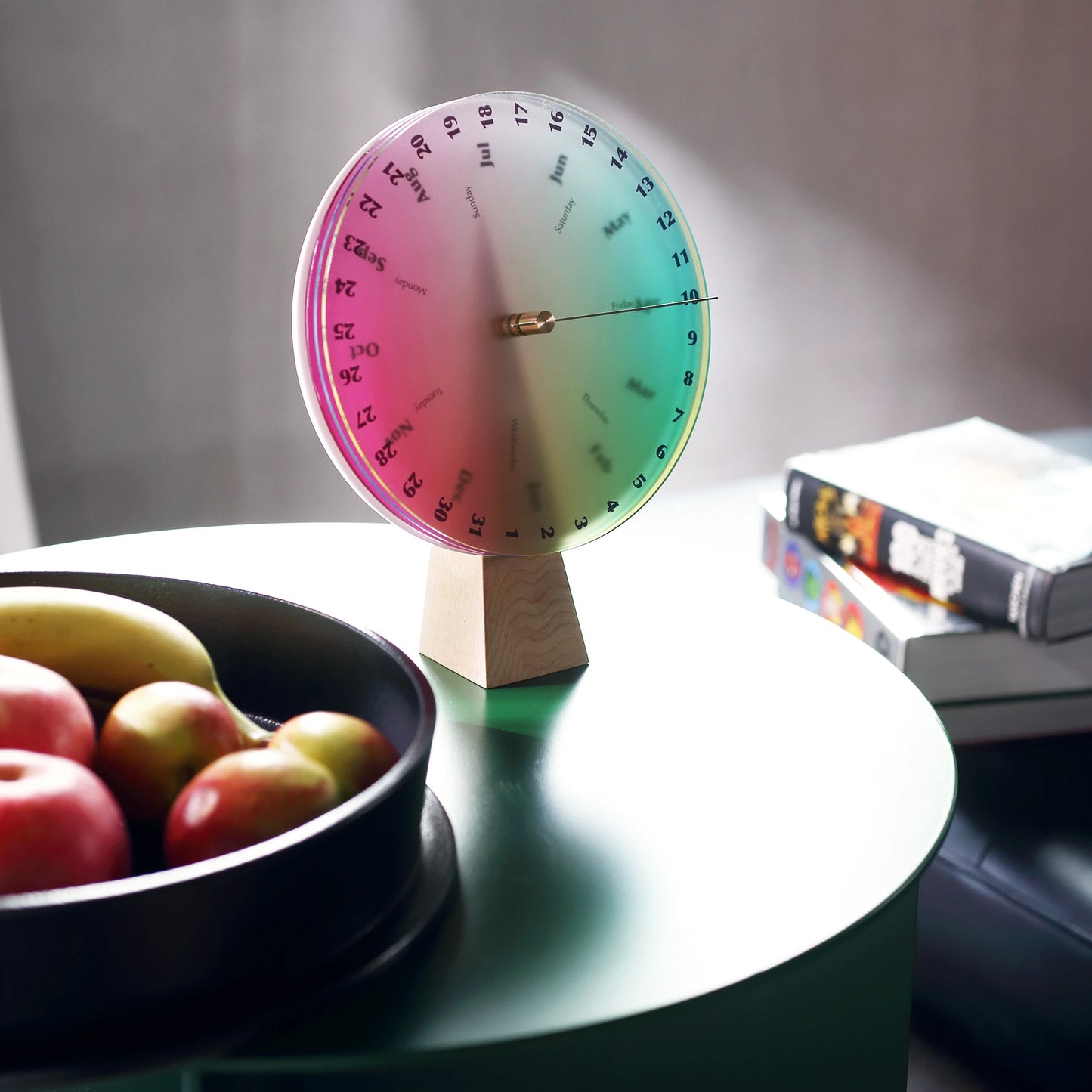 A colorful perpetual calendar styled on a modern green side table.