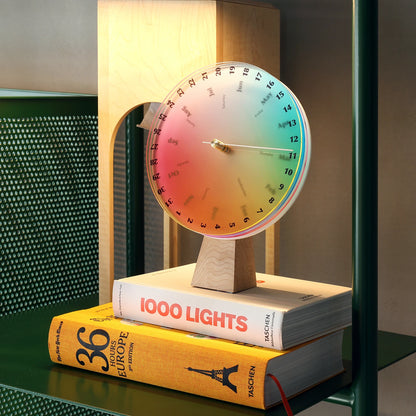 A modern color wheel calendar displayed on a stack of art books.