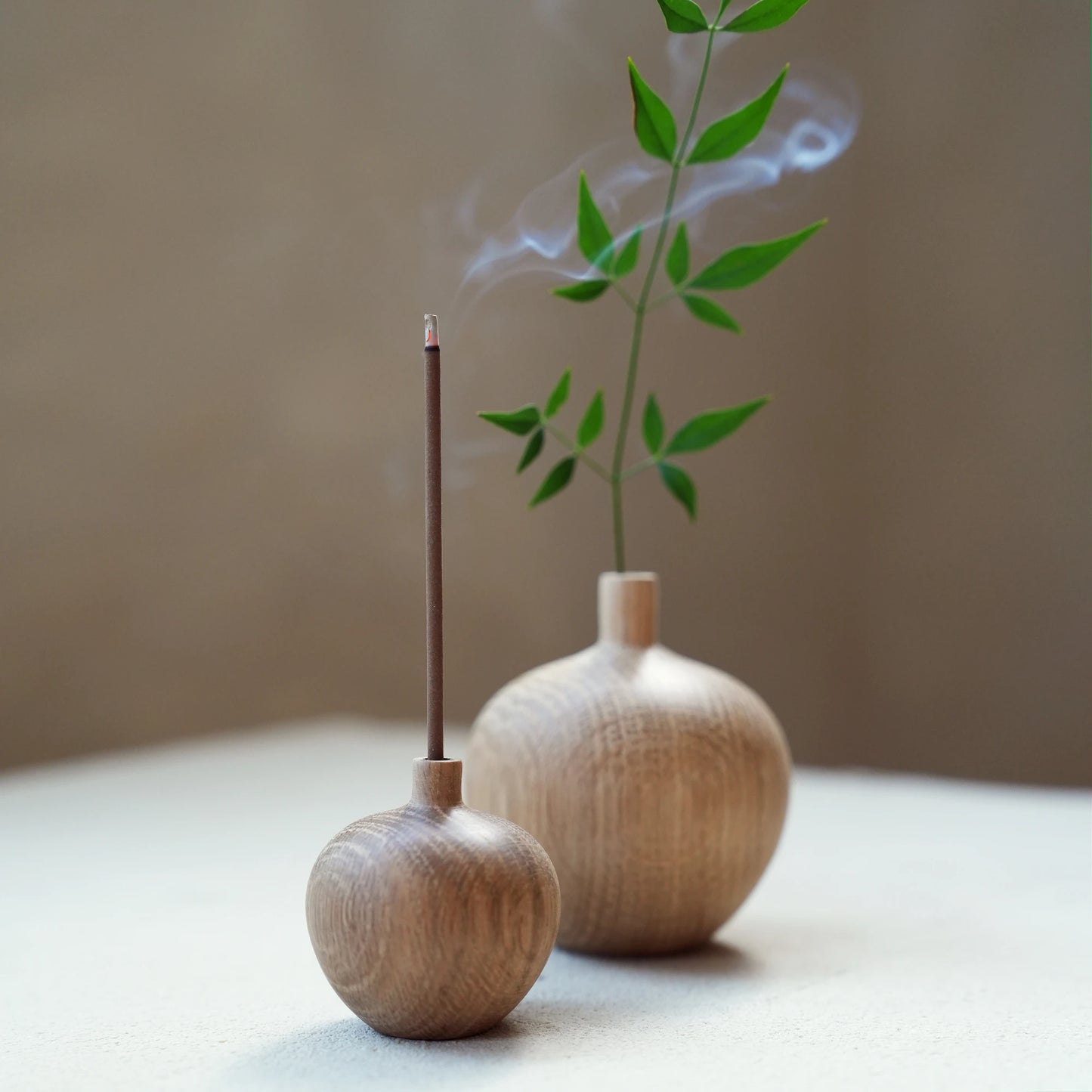 A small oak wood vase being used as a minimalist incense stick holder.