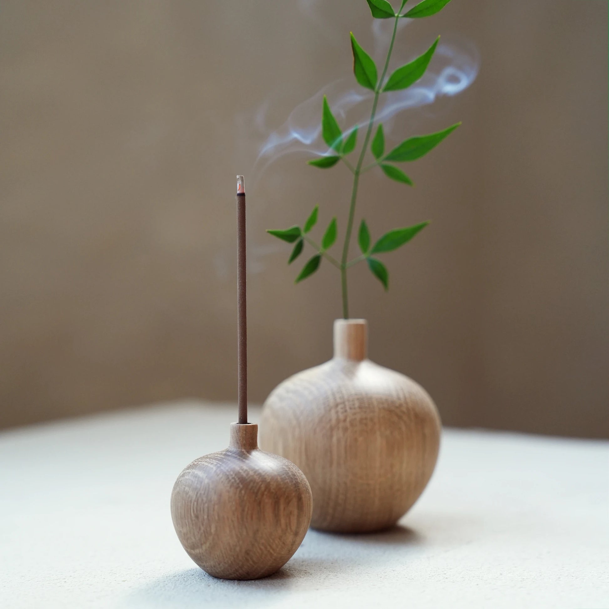 A small oak wood vase being used as a minimalist incense stick holder.