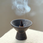 Close-up of smoke and an incense cone in a wabi-sabi ceramic burner.