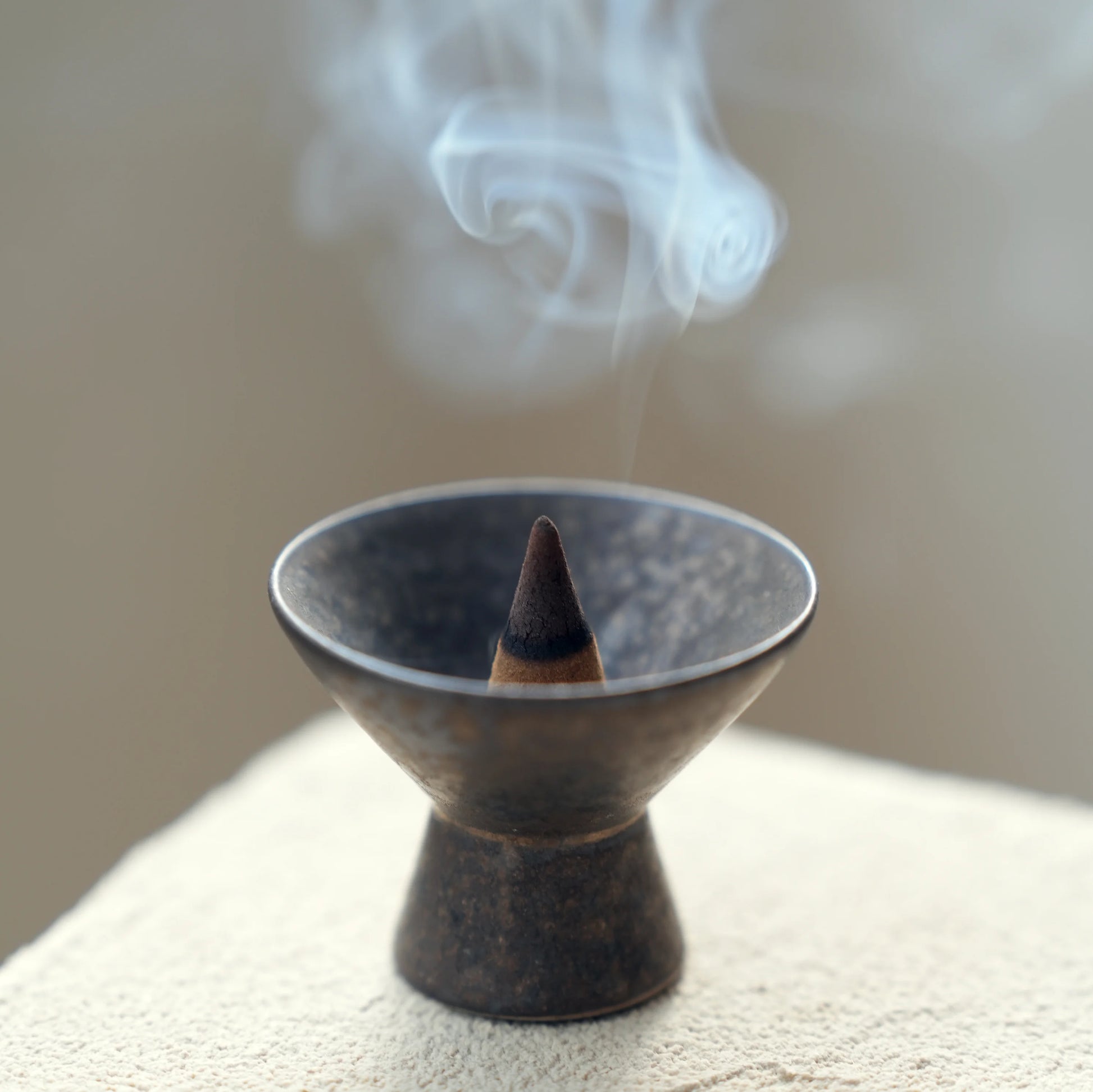 Close-up of smoke and an incense cone in a wabi-sabi ceramic burner.