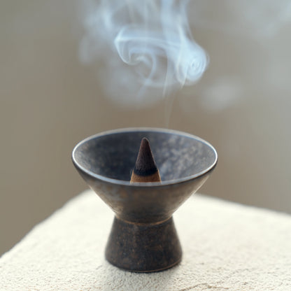 Close-up of smoke and an incense cone in a wabi-sabi ceramic burner.