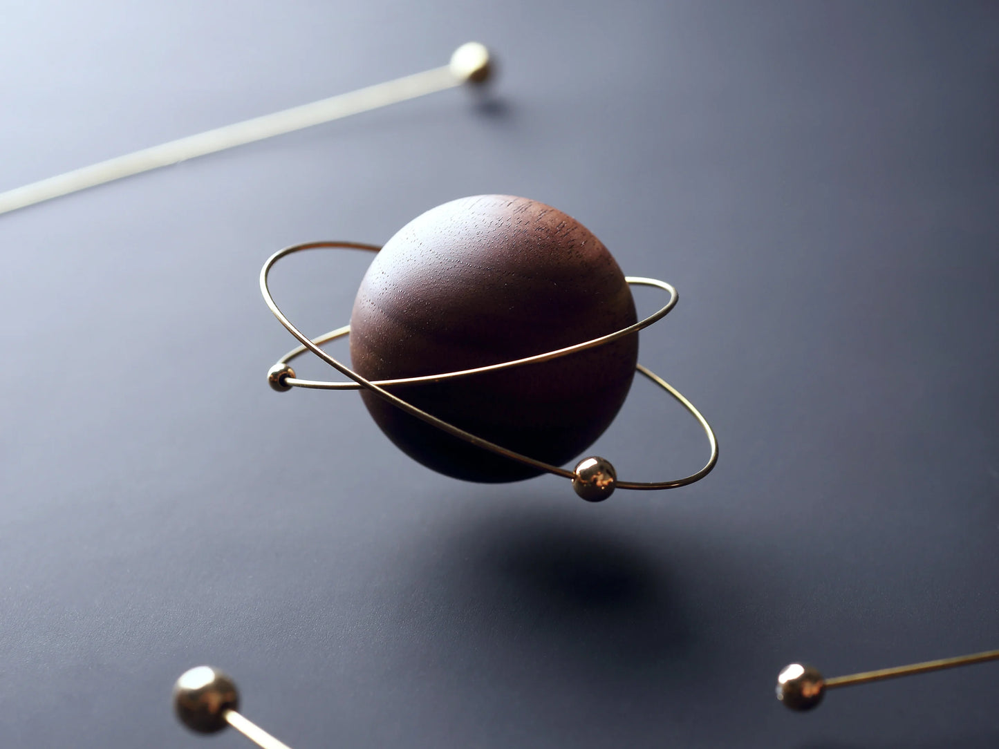 Close-up of the walnut and gold-plated planet with orbiting rings.