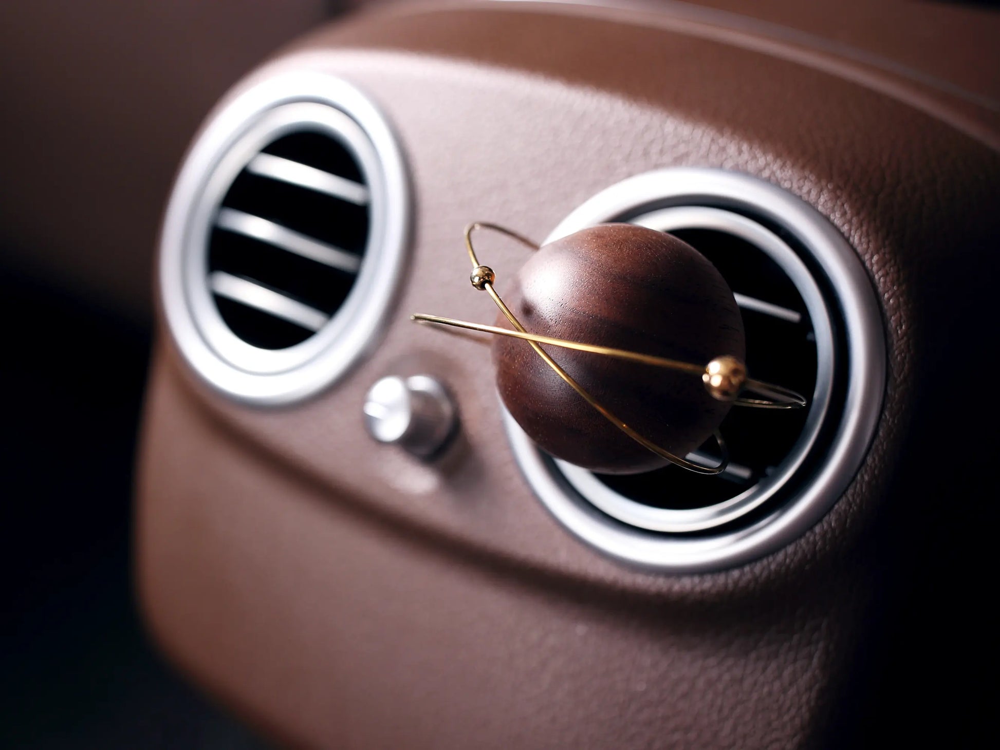 Angled view of the planet car vent diffuser in a leather interior.