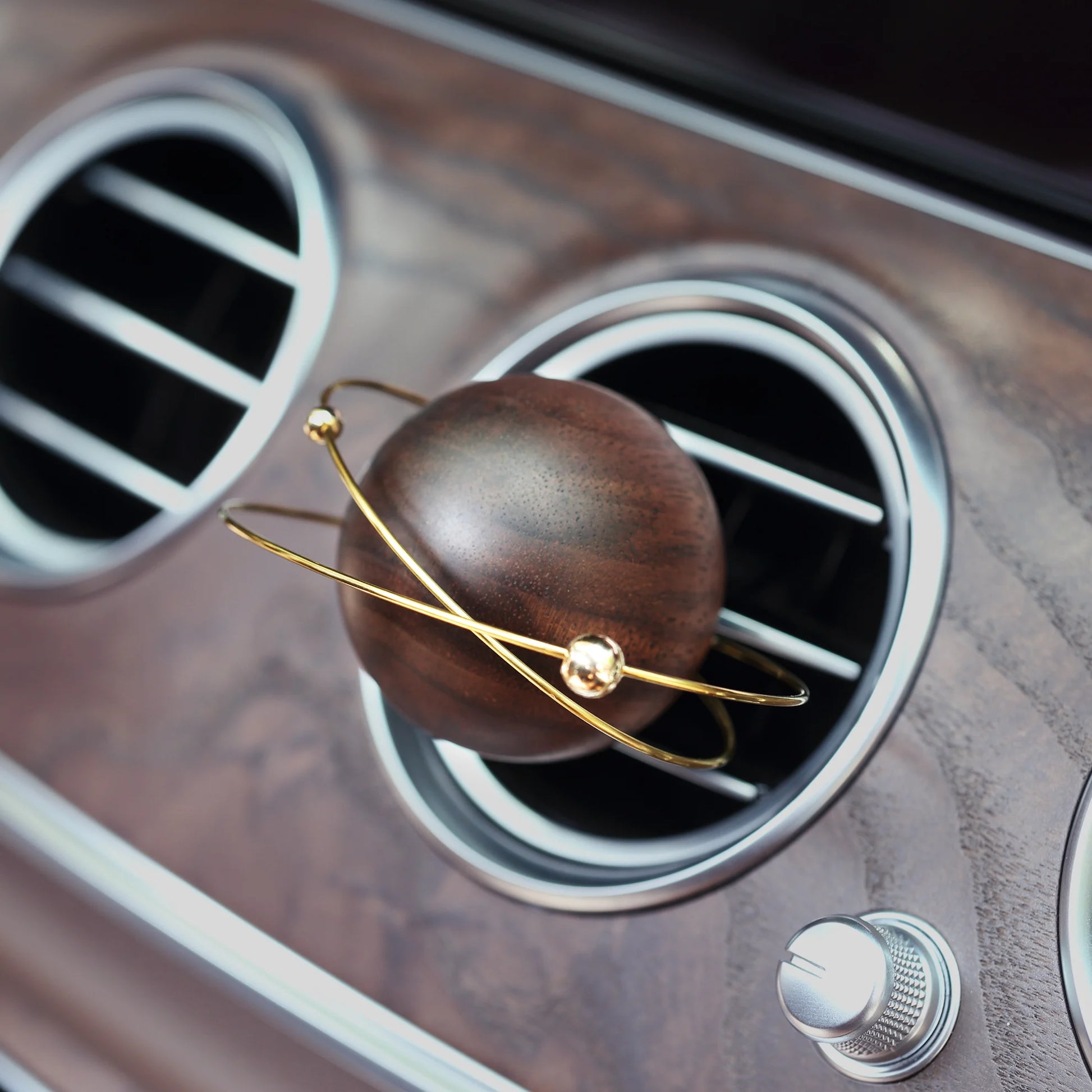 A wooden planet car diffuser in a luxury car with a wood grain dash.
