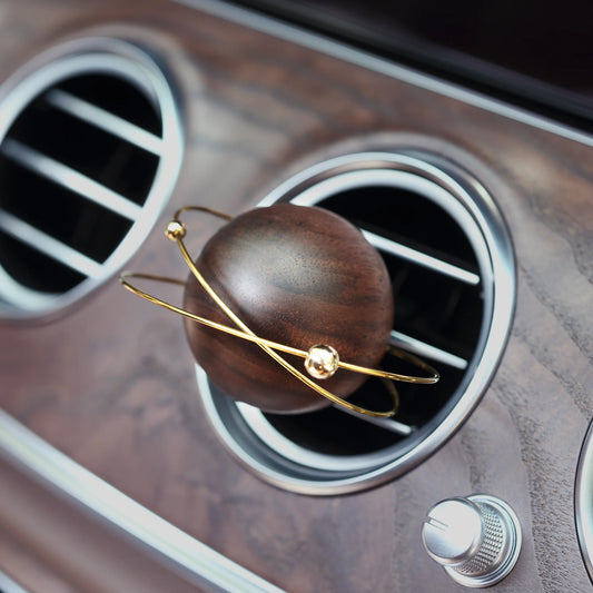 A wooden planet car diffuser in a luxury car with a wood grain dash.