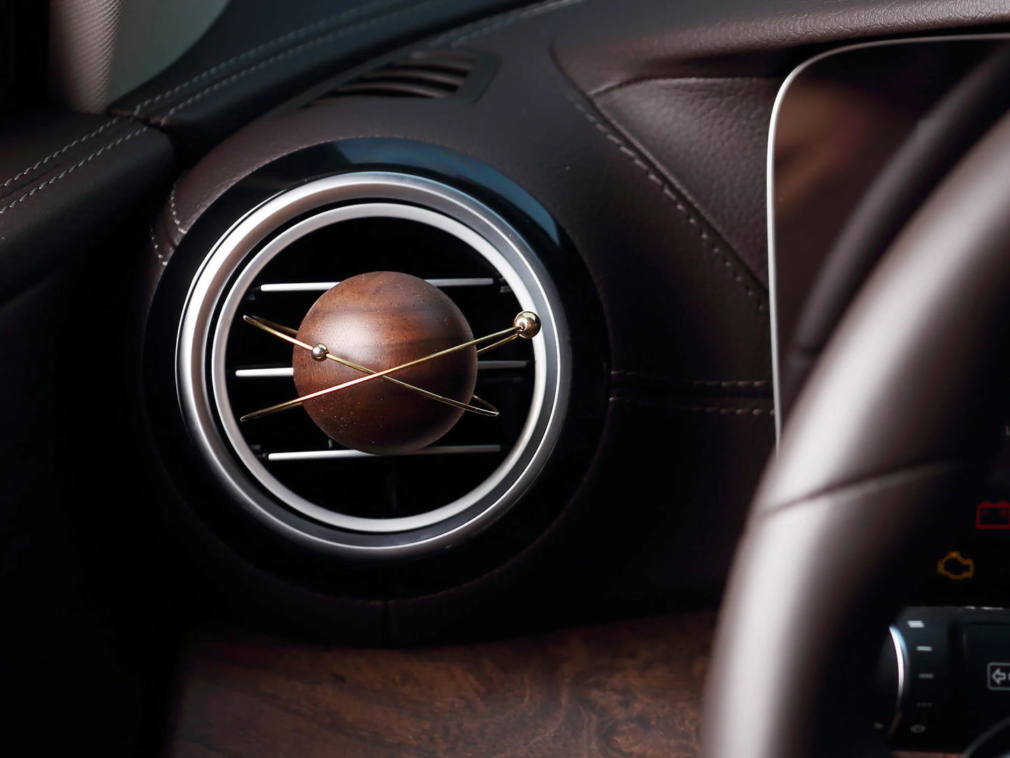 A planet-shaped car diffuser clipped to a circular car air vent.