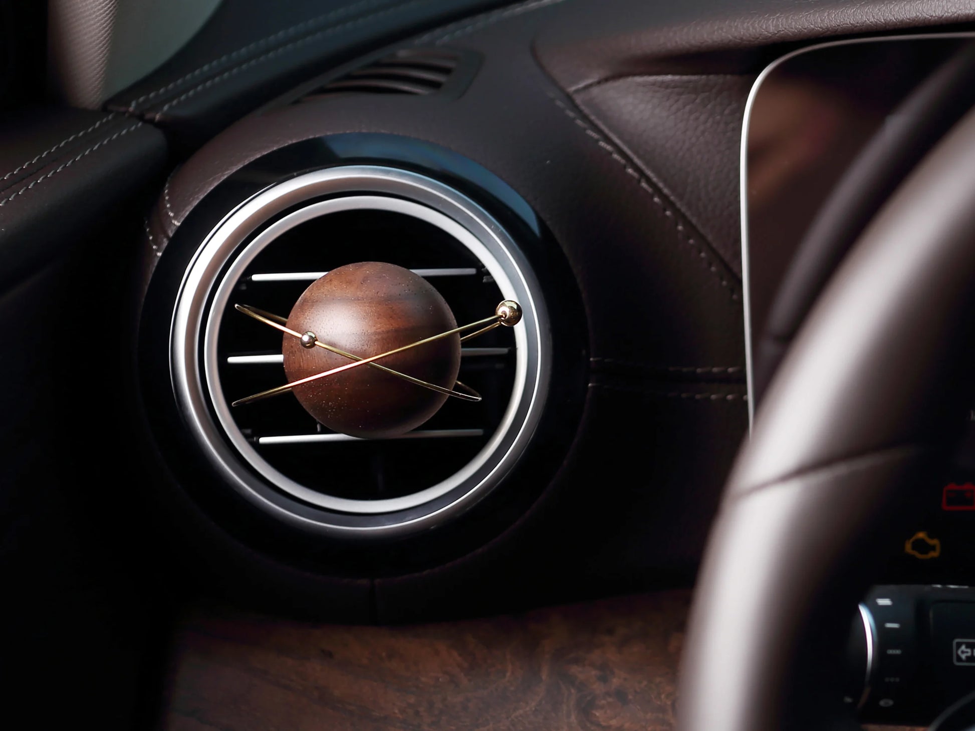 A planet-shaped car diffuser clipped to a circular car air vent.