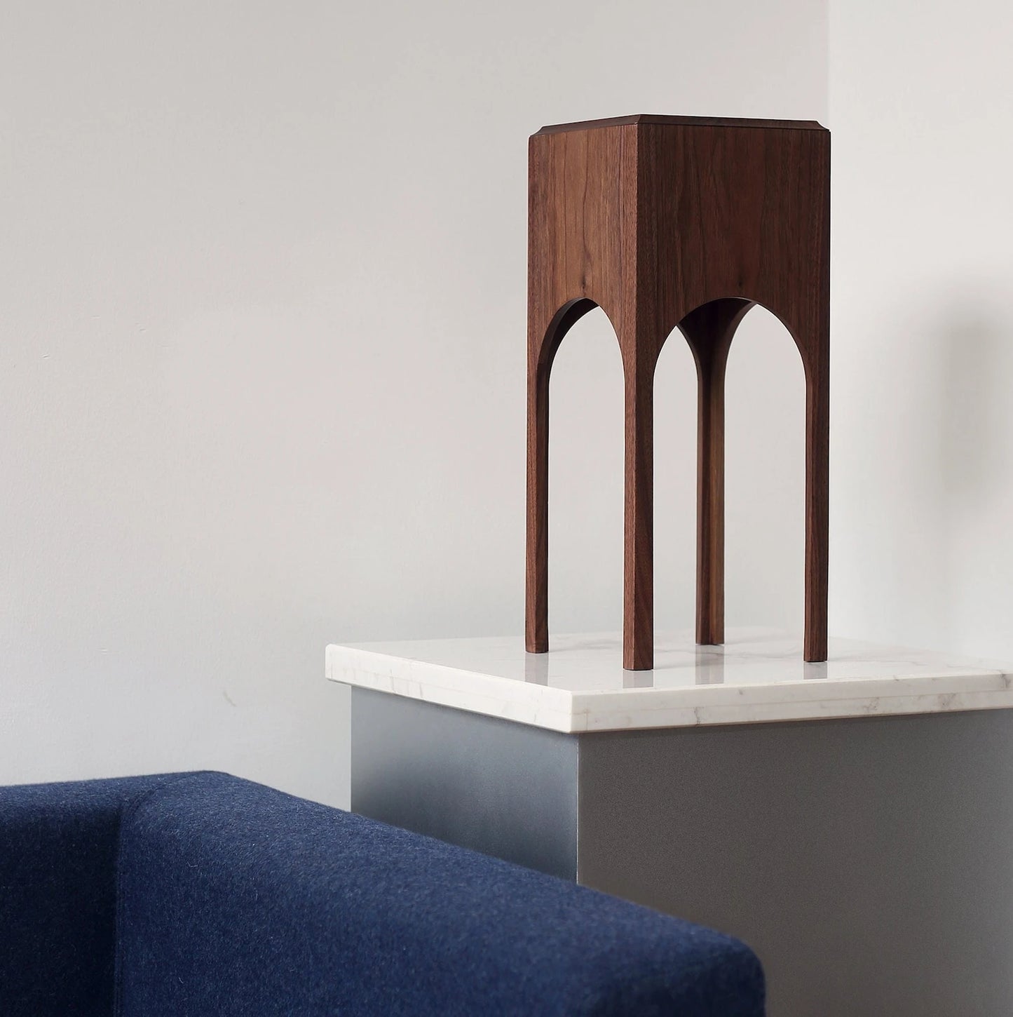 The walnut architectural tissue box styled on a cabinet next to a blue sofa.