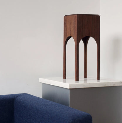 The walnut architectural tissue box styled on a cabinet next to a blue sofa.