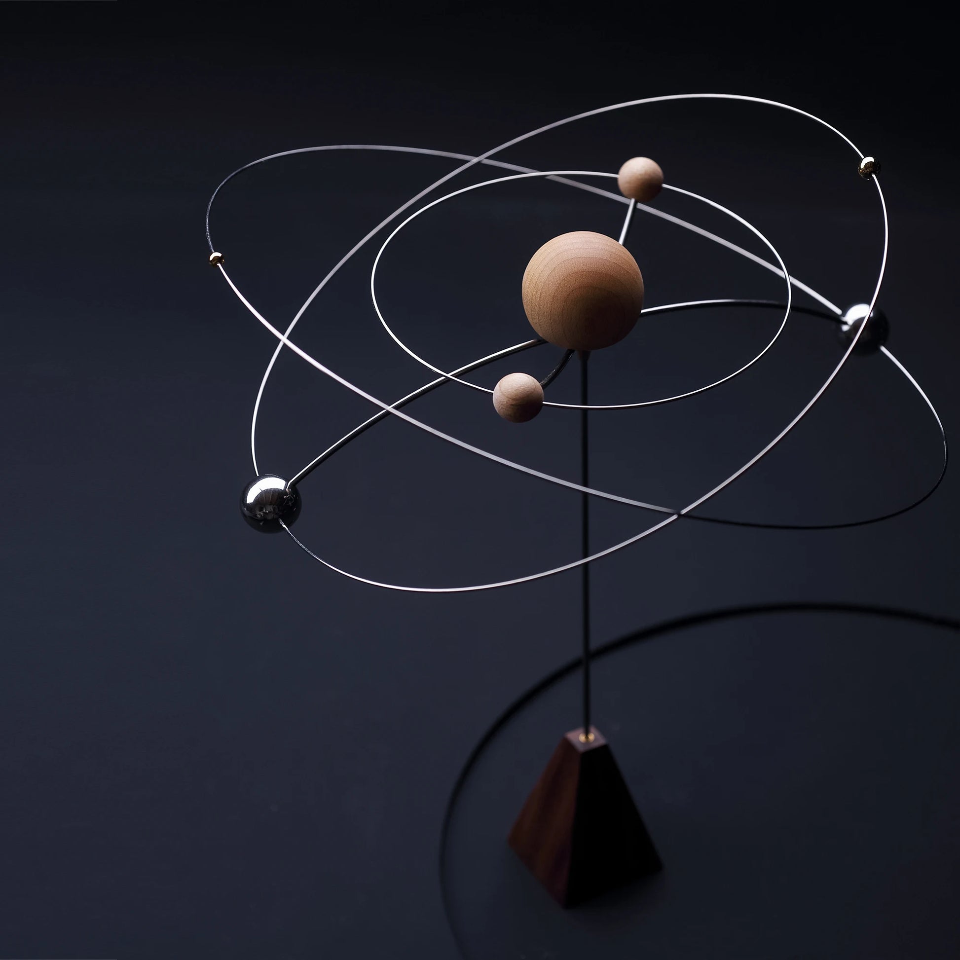 A kinetic galaxy scent diffuser with orbiting spheres in low light.