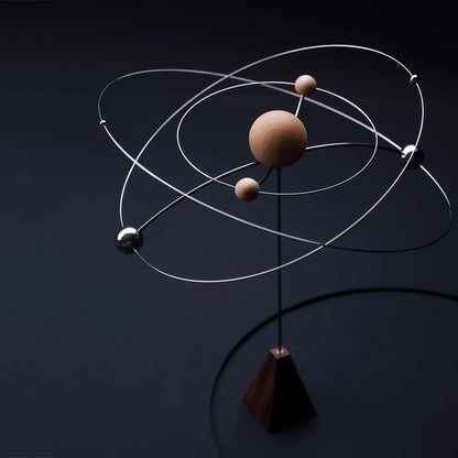A kinetic galaxy scent diffuser with orbiting spheres in low light.