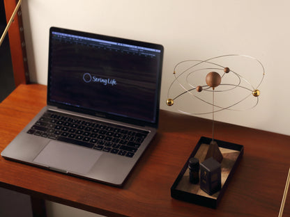 The kinetic scent diffuser styled on a modern wood desk with a laptop.