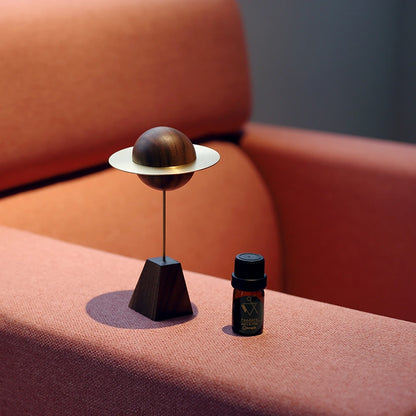 A minimalist planet-shaped scent diffuser sitting on an orange sofa.