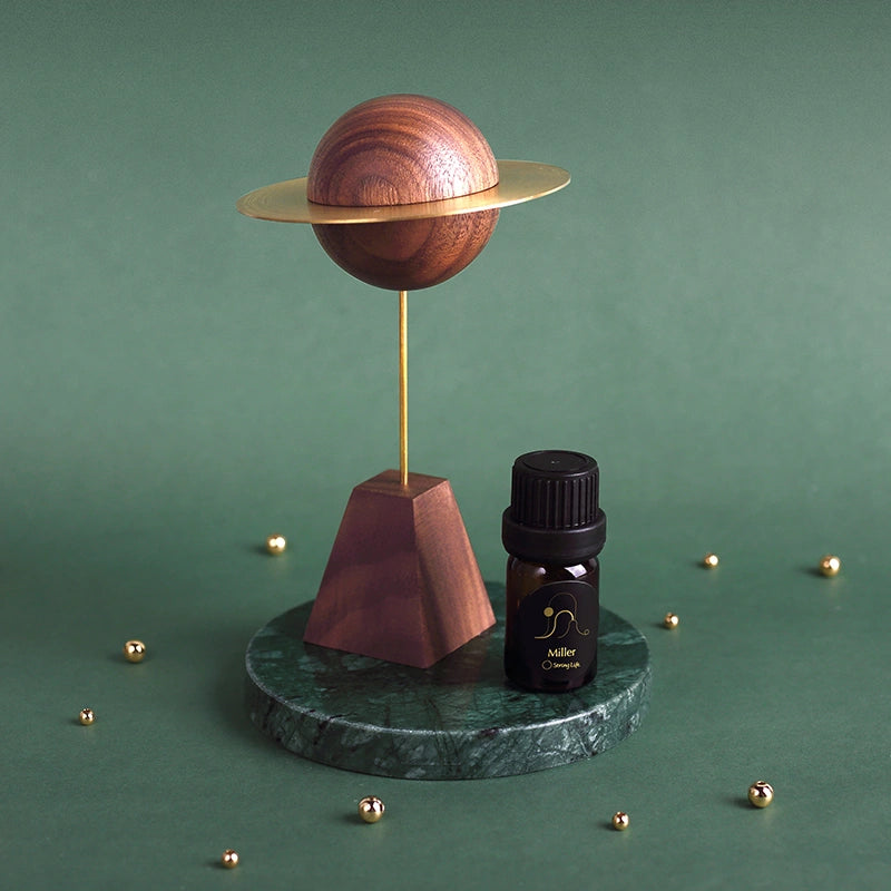 Walnut and brass planet diffuser styled on a green marble surface.