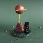 Walnut and brass planet diffuser styled on a green marble surface.