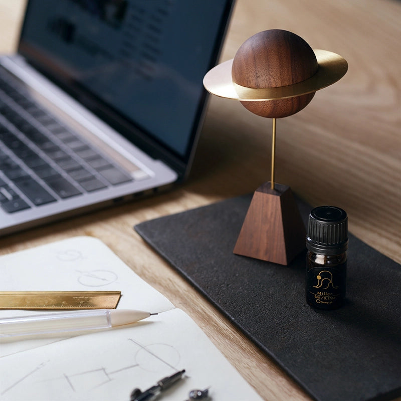A walnut planet scent diffuser on a desk next to a laptop.