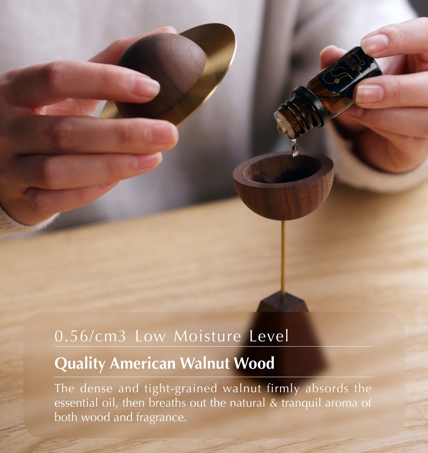 Hands adding essential oil to the top of the wooden planet diffuser.