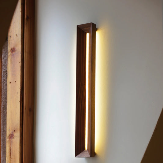 A minimalist walnut LED light mounted vertically in a dramatic sunbeam.