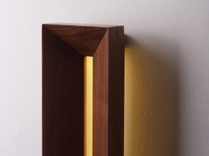 Close-up of the beveled edge and warm glow of the architectural wood sconce.