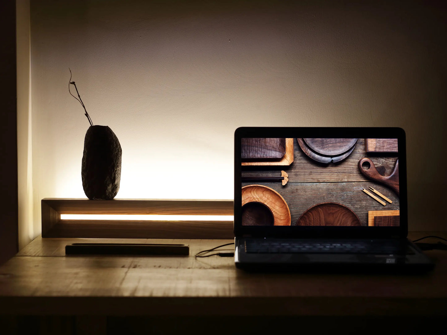 A walnut LED lamp resting horizontally on a desk as an ambient task light.