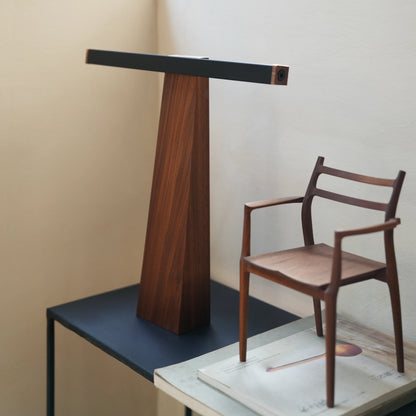 Walnut desk lamp styled next to a small wooden chair on stacked books.