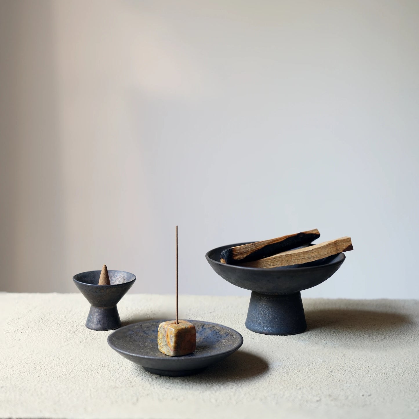A collection of three different ceramic and stone incense holders.