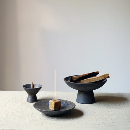 A collection of three different ceramic and stone incense holders.