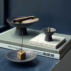 Wabi-sabi style incense holders displayed on stacked books.