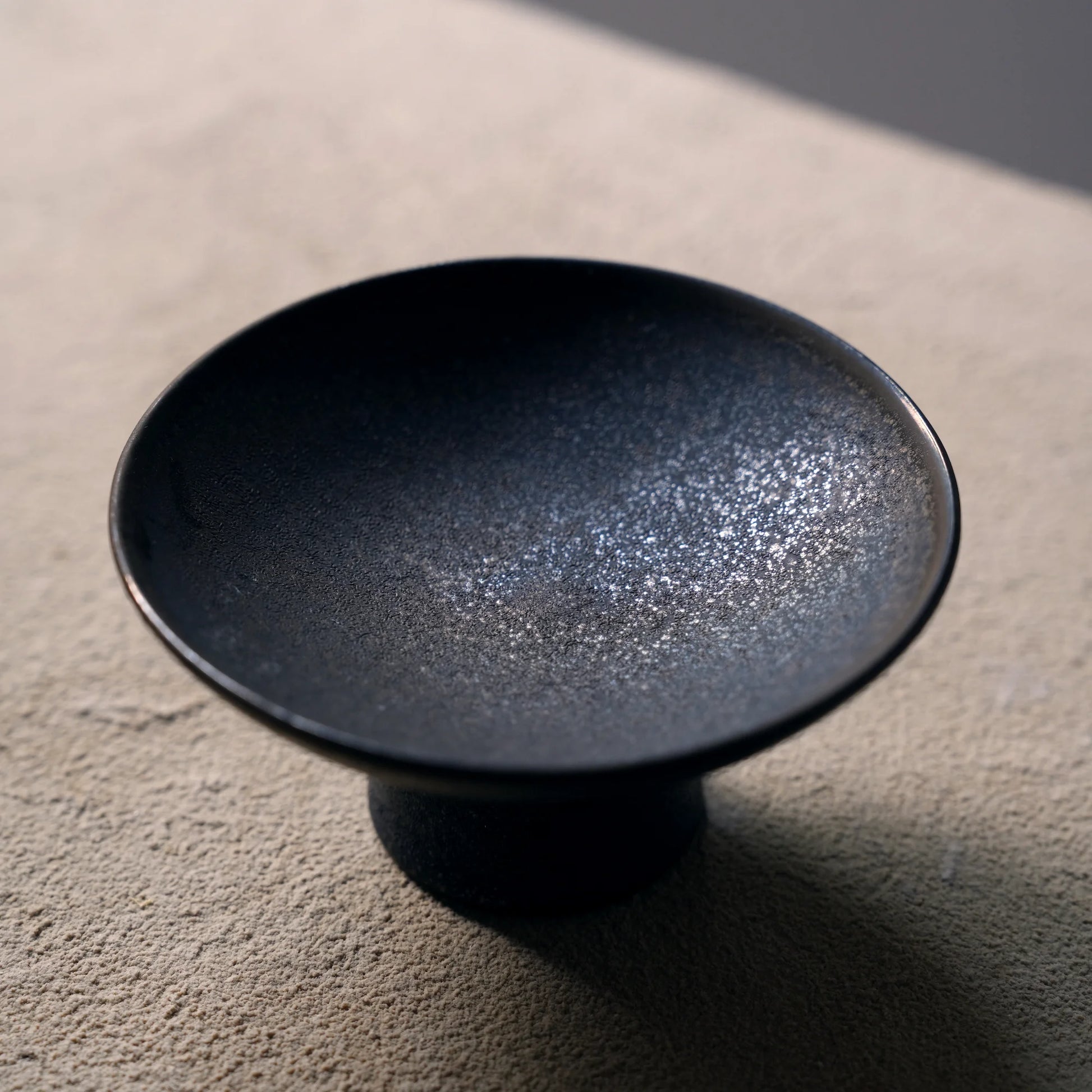 Close-up of the textured mottled glaze on a black ceramic dish.