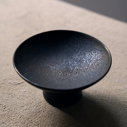 Close-up of the textured mottled glaze on a black ceramic dish.