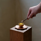 Hand tapping a mini brass singing bowl with a stone-tipped striker.