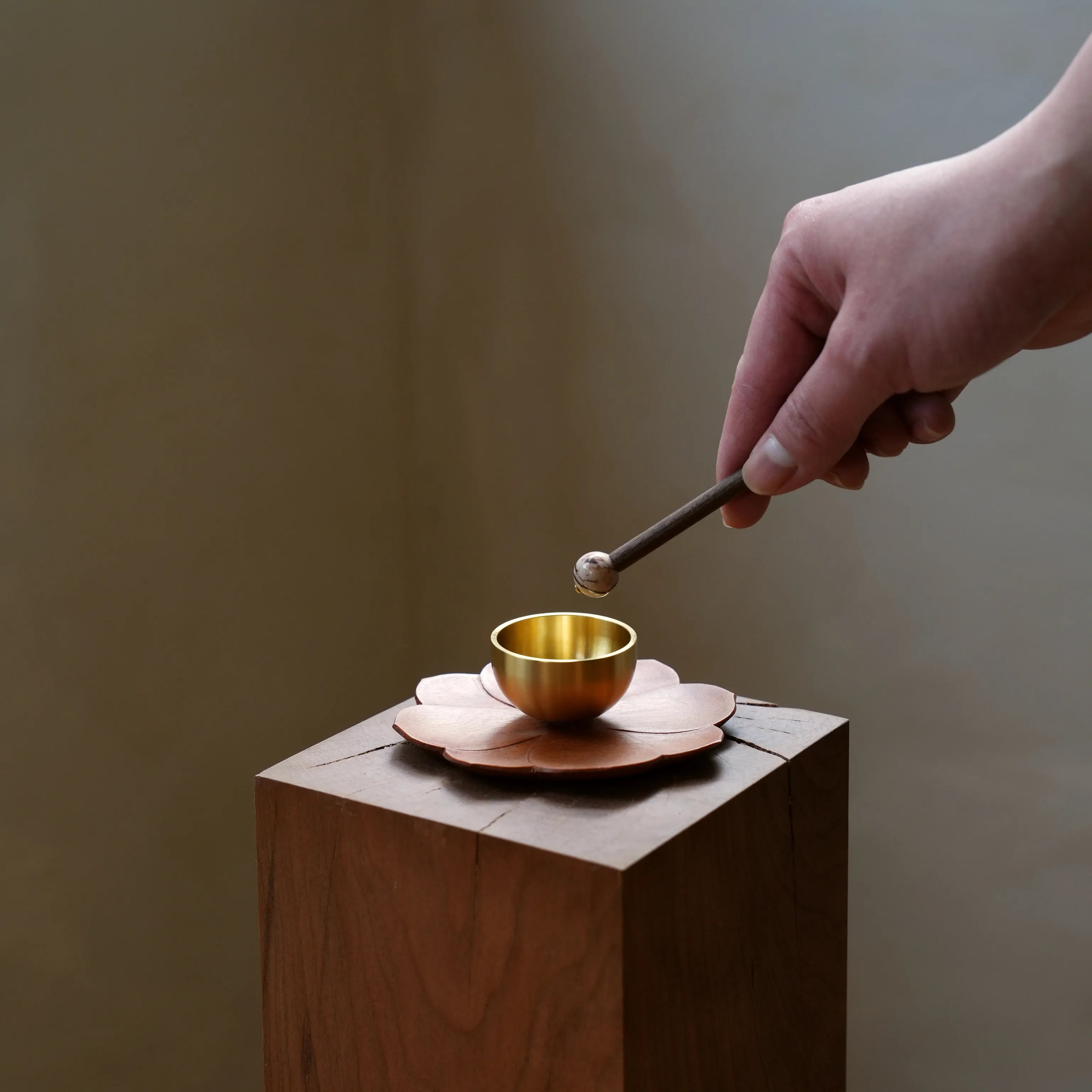 Hand tapping a mini brass singing bowl with a stone-tipped striker.