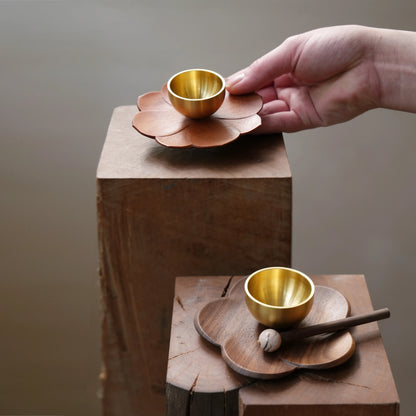 Hand placing a small singing bowl set on a wooden display block.