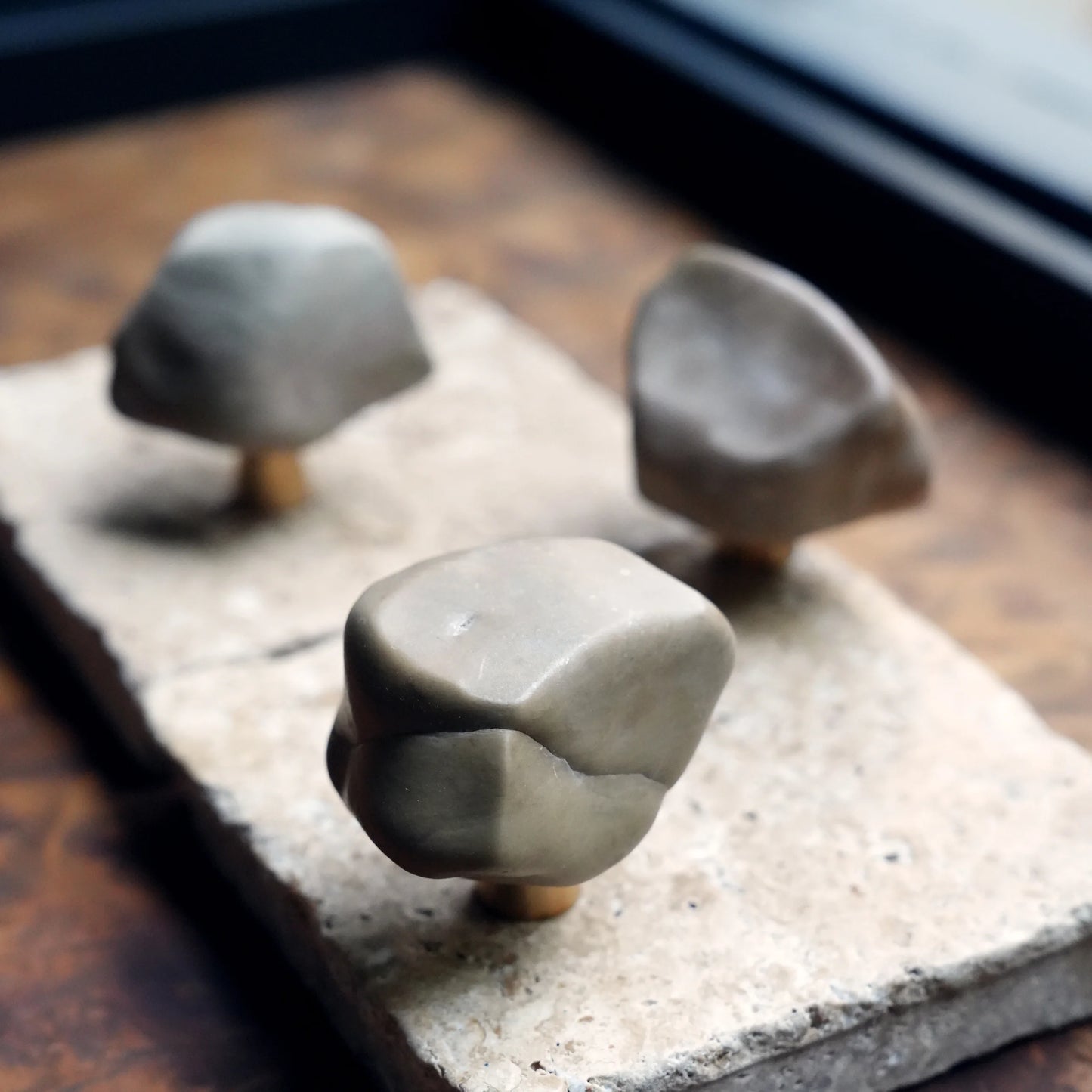 Three natural Gobi stone drawer pulls on a travertine slab.