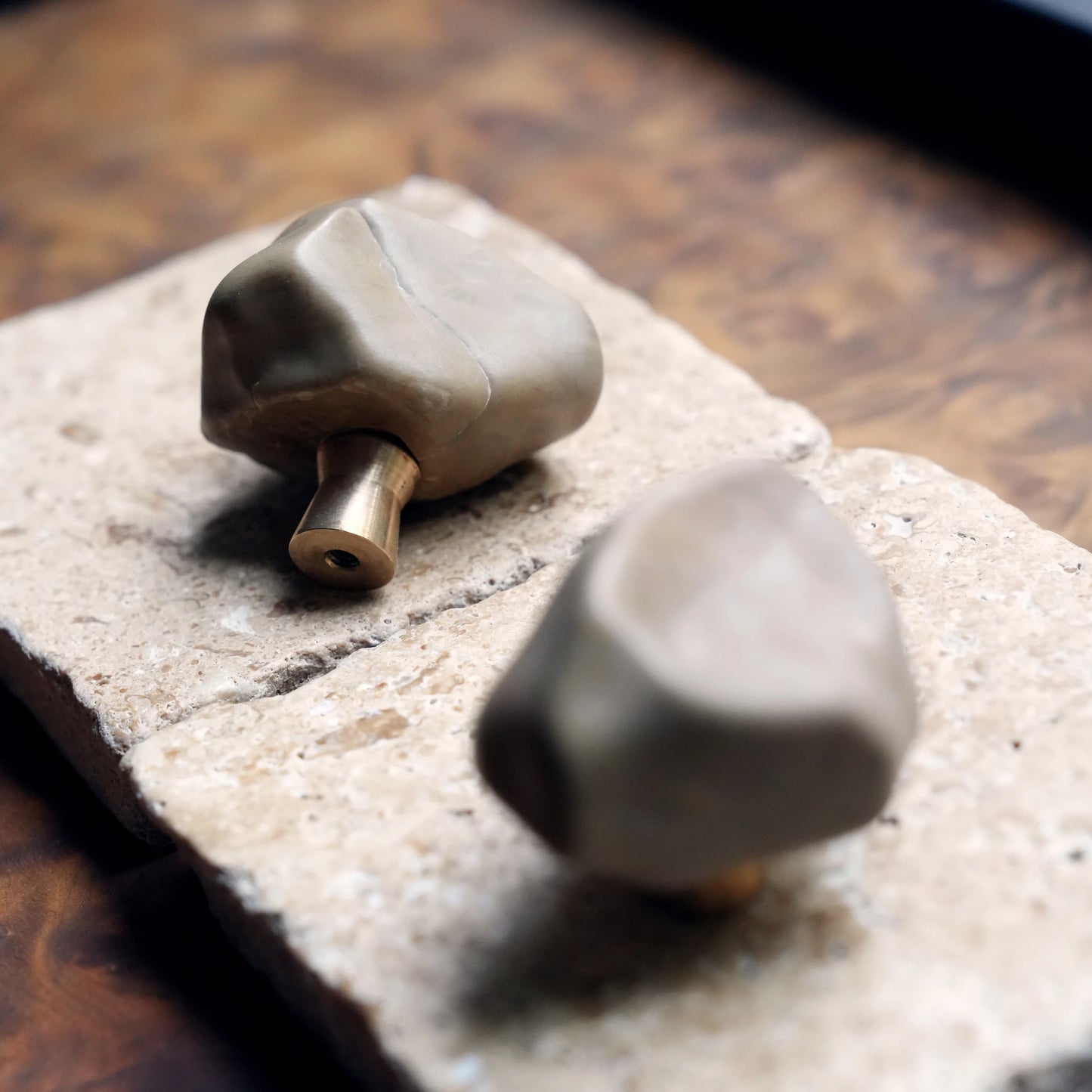 Close-up of brass base on two organic stone cabinet knobs.