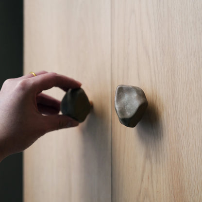 Hand turning a Gobi stone cabinet knob on a light wood cabinet door.