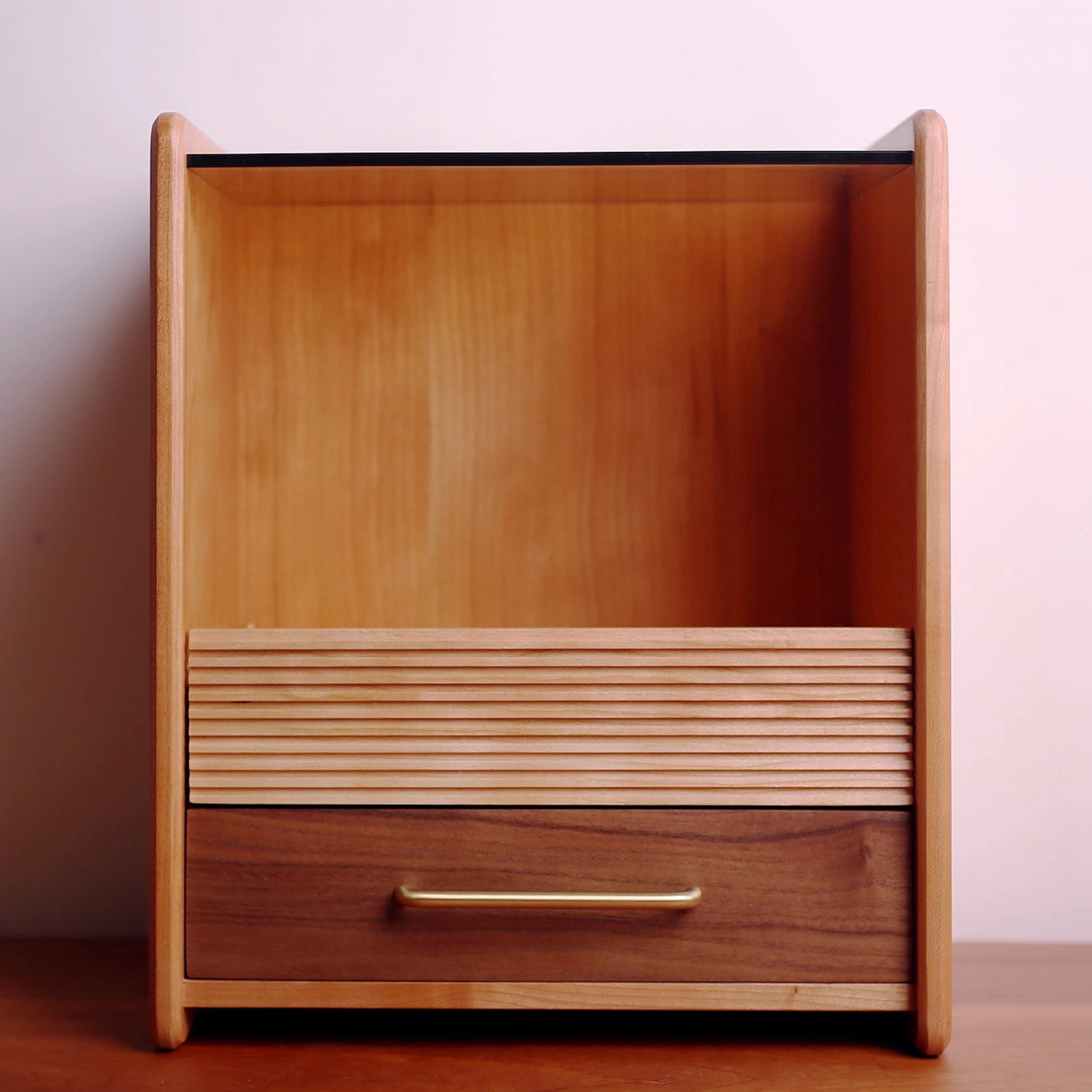 Front view of reeded wood makeup organizer with glass top shelf.