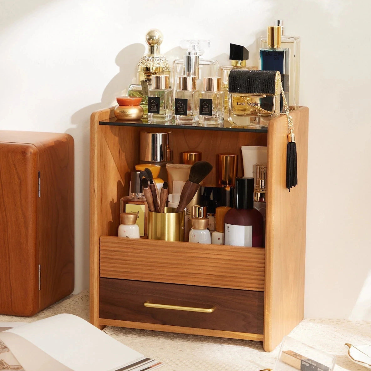 Wood vanity organizer full of perfume and skincare on a bright desk.